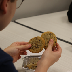  a close up of a student holding a cookie while at a table